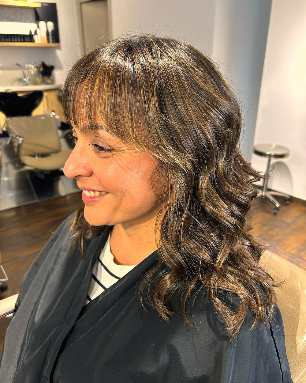 Media melena castaña con flequillo y ondas, peinada en el salón