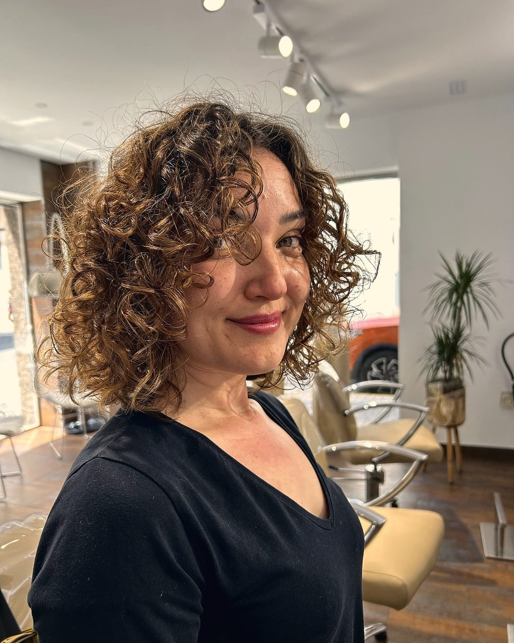 Melena rizada castaña con reflejos, definida en el salón
